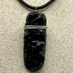 Ciondolo in ossidiana naturale intagliata a mano, con cordino nero regolabile.